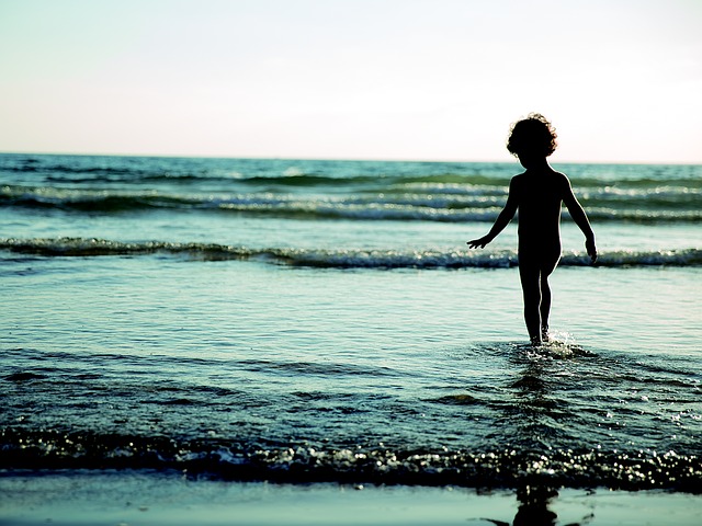 little boy walking in ocean
